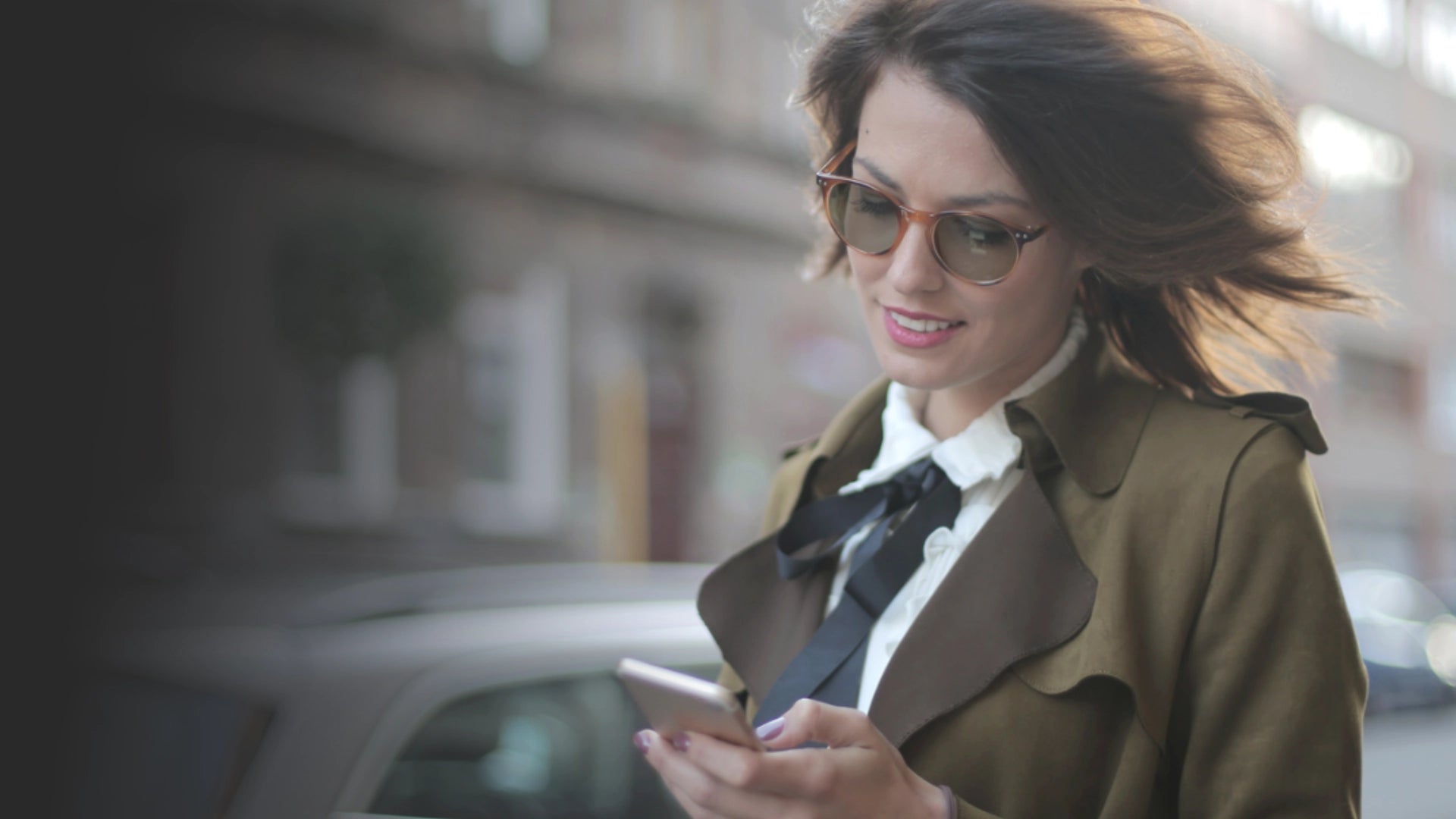 Person walking down street looking at their phone while wearing Avulux migraine glasses