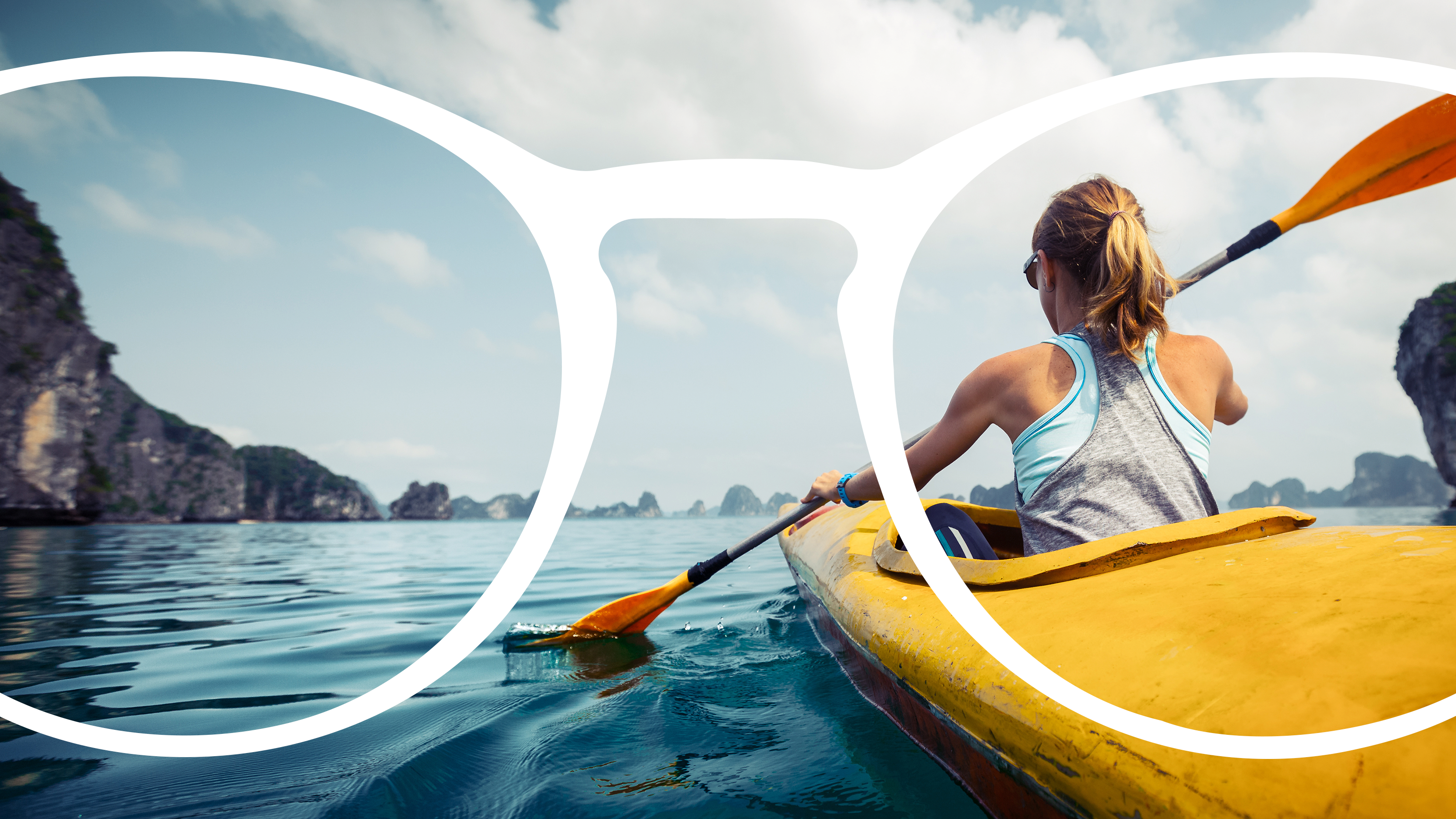 World without Avulux lenses: A kayaker on turquoise water surrounded by cliffs, paddling a yellow kayak against a blue sky with white clouds.