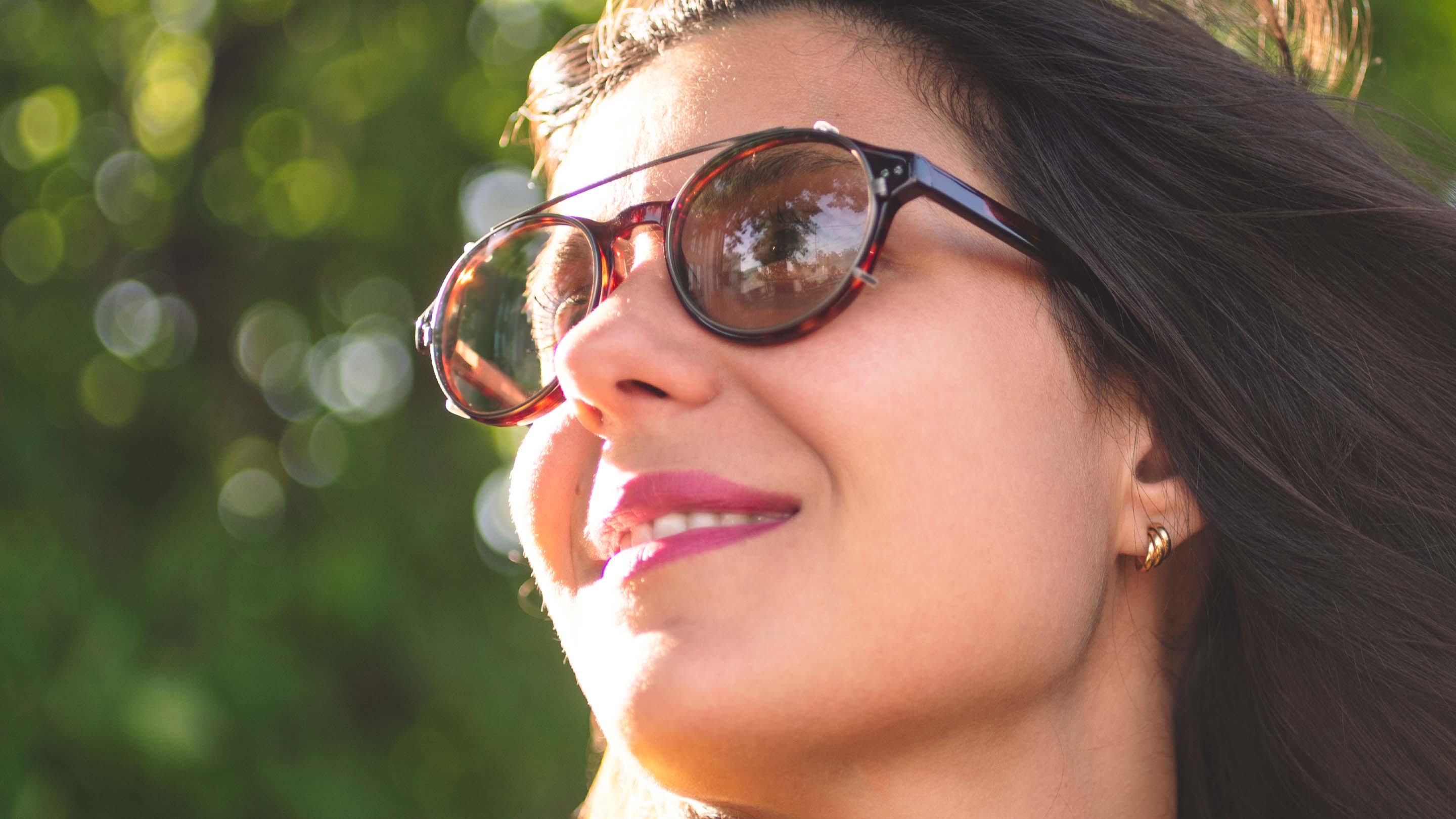 Headshot of woman wearing Avulux migraine glasses outdoors.