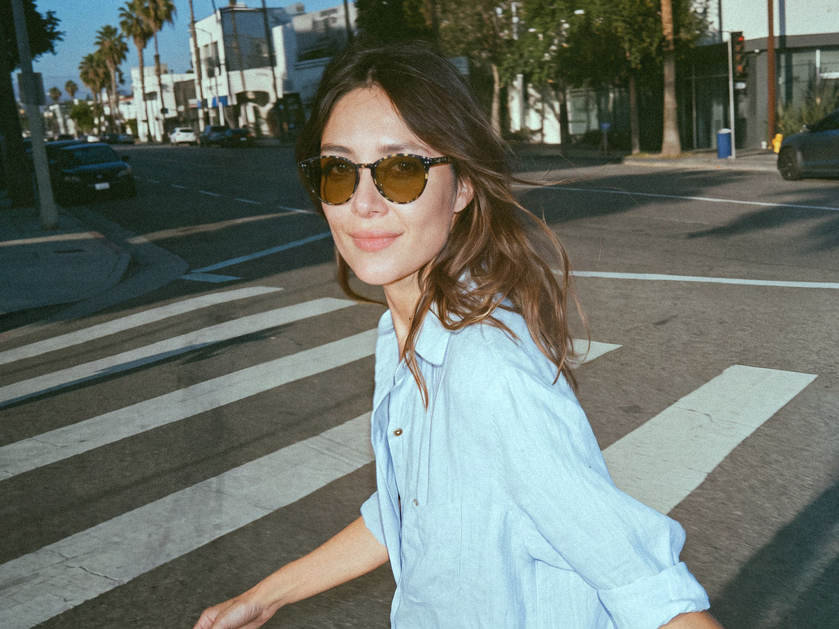 Woman walking outside in wearing Avulux Adapt lenses in Lilu Havana Night frames