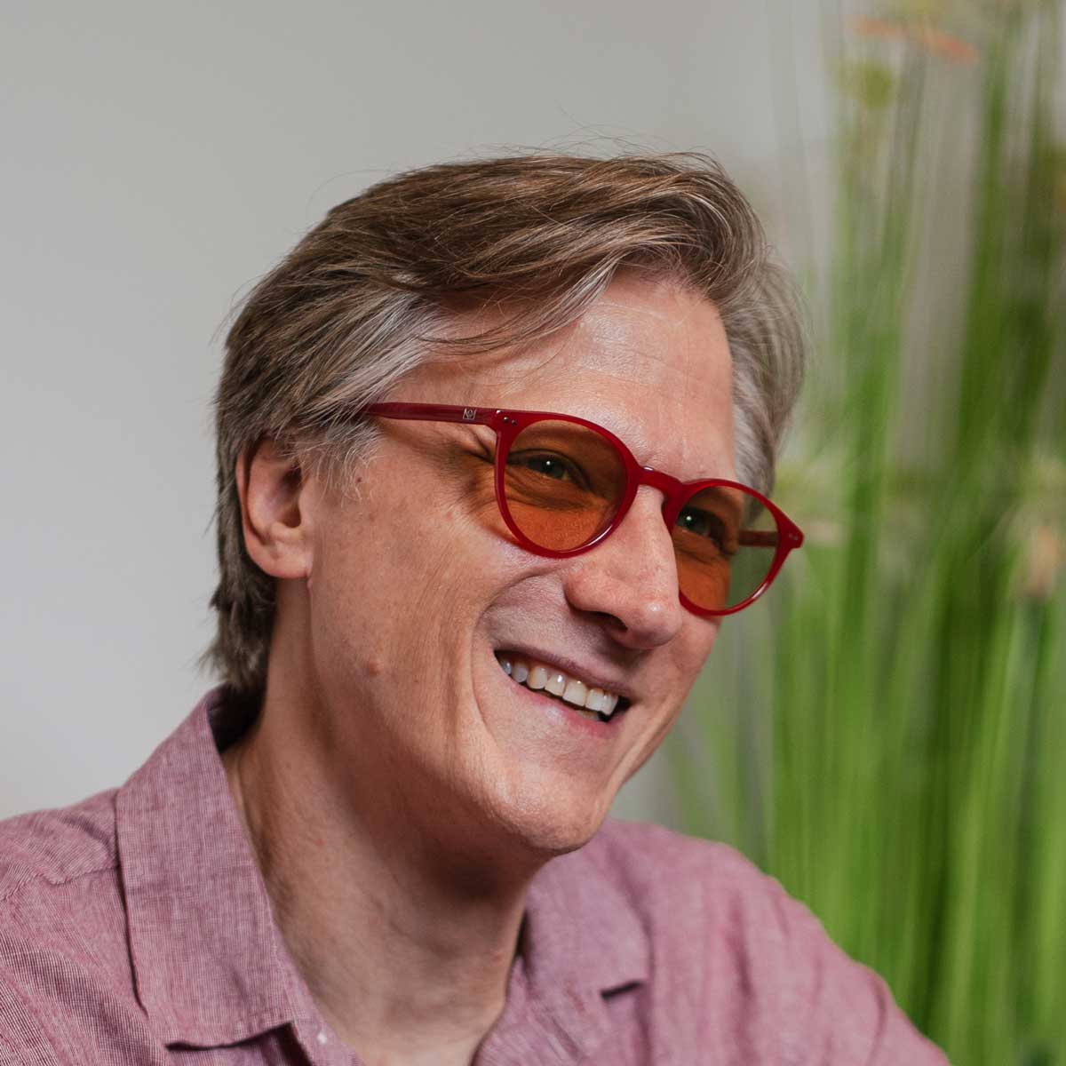 Close-up portrait of a man wearing Lilu Red Avulux migraine glasses, designed to help manage light sensitivity for people living with migraine.