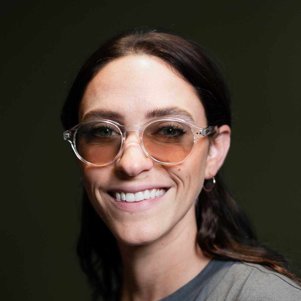 Close-up portrait of a woman wearing Bli Clear Avulux migraine glasses, designed to help manage light sensitivity for people living with migraine.