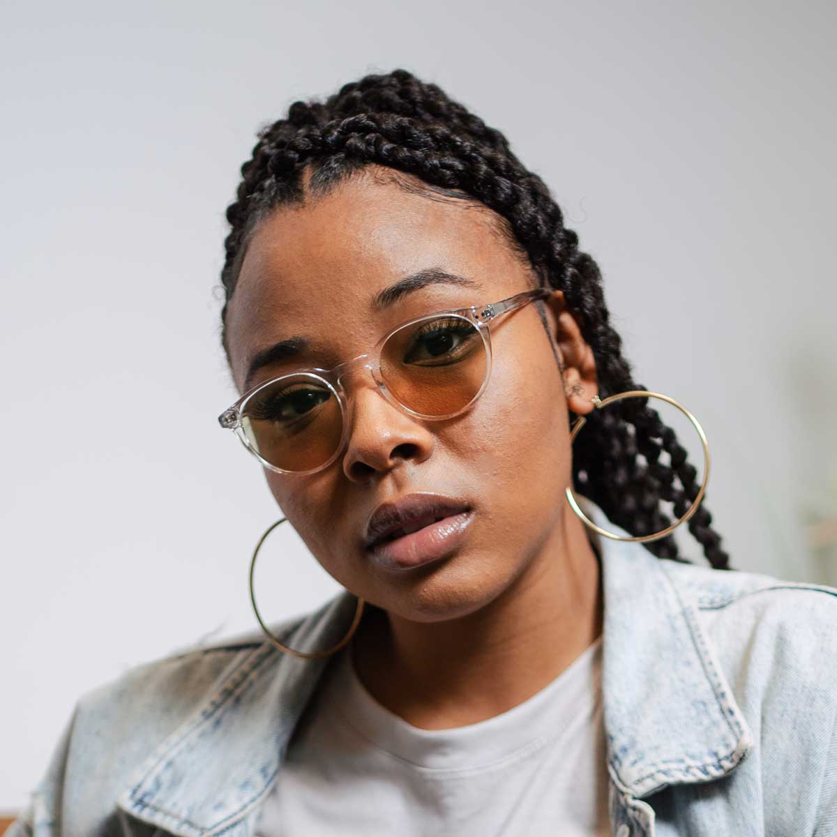 Close-up portrait of a woman wearing Lilu Clear Avulux migraine glasses, designed to help manage light sensitivity for people living with migraine.