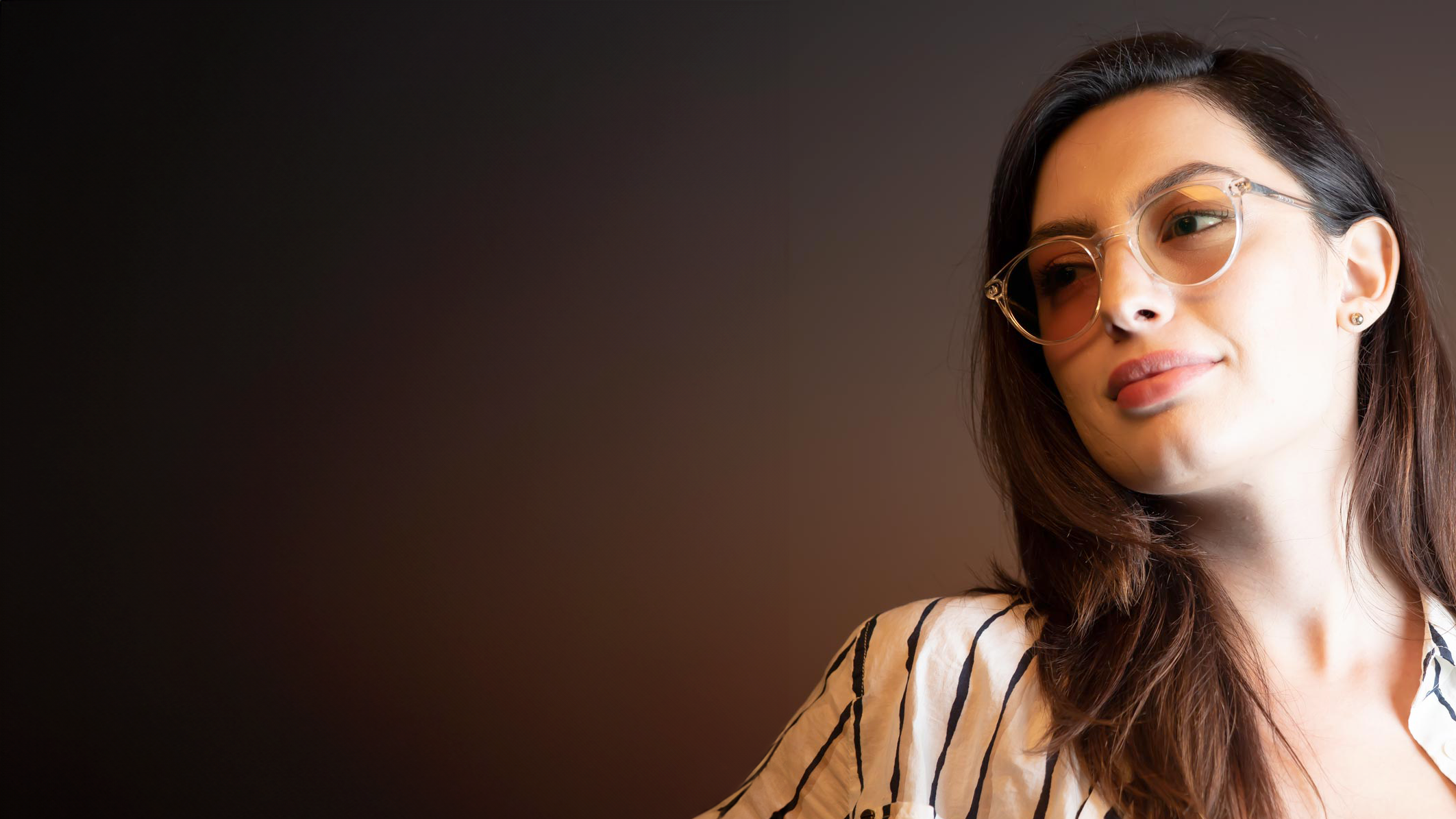 Woman wearing Avulux Migraine Glasses set against a dark background